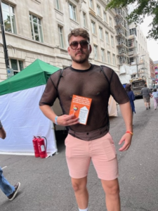 Pride in London 2023 attendee with our LGBTQ+ leaflet and Pride stickers.