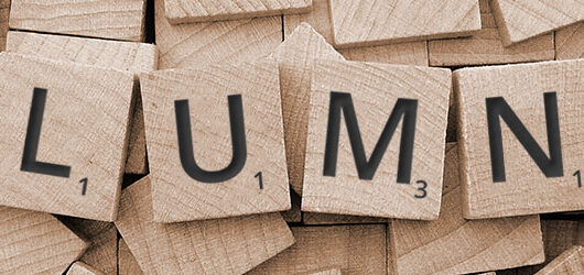 A graphic showing the word alumni spelt out with wooden scrabble-style tiles.