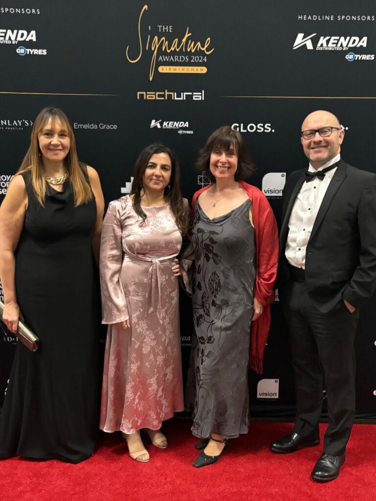 Gordon Moody colleagues Monica Shafaq, Julia Herdman, Victoria Jackson, and Jon Murray pose in front of the Signature Awards 2024 background.