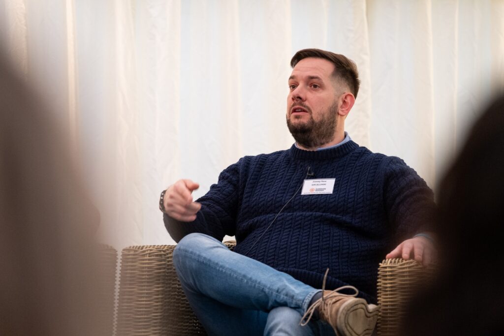 A male Gordon Moody alumni wearing a blue jumper speaks on stage at the official opening of Gordon Moody House in Redditch on Monday 25th November 2024.