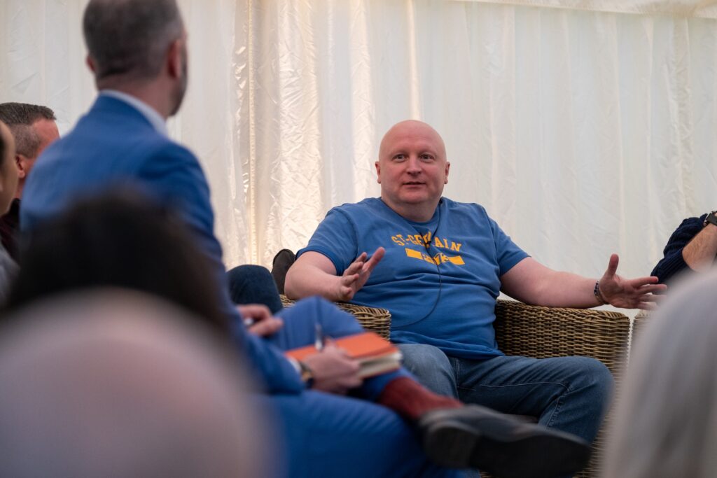 A male Gordon Moody alumni wearing a blue t-shirt speaks on stage at the official opening event for Gordon Moody House in Redditch on Monday 25th November 2024.